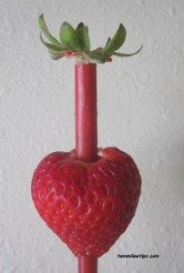 Straw pushing through the top of a strawberry