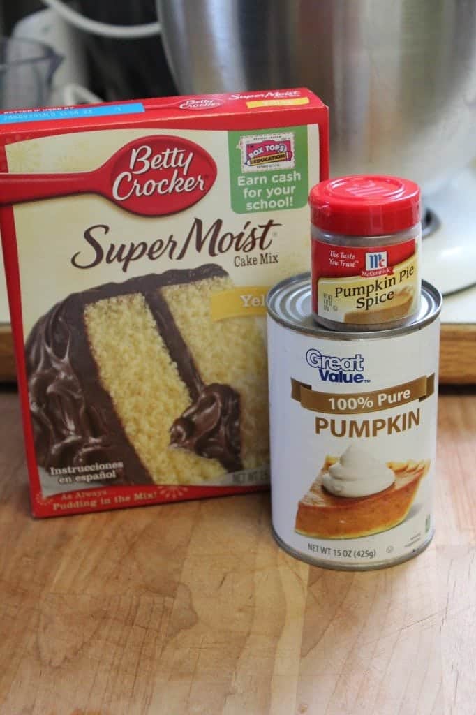 Yellow cake mix, canned pumpkin, an pumpkin pie spice on a wood cutting board