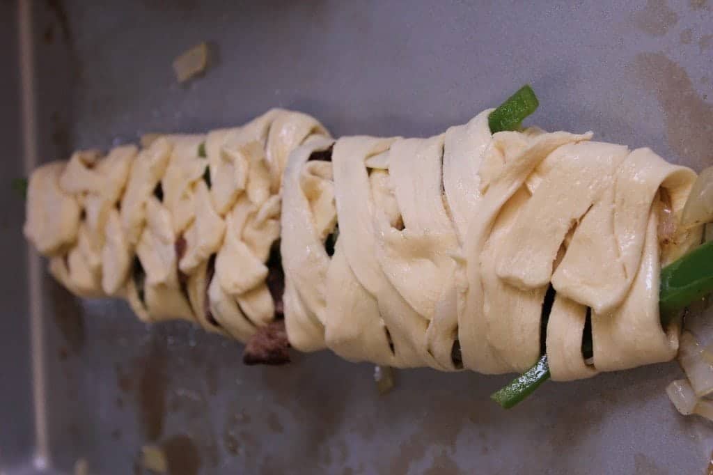 unbaked crescent cheesesteak braid on a baking sheet. 