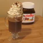 Nutella hot chocolate topped with whipped cream in front of a nutella container