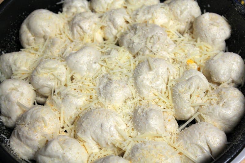 Biscuit dough balls covered in parmesan cheese in a baking dish