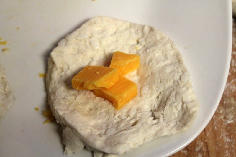 biscuit dough with pieces of cheese on a white plate