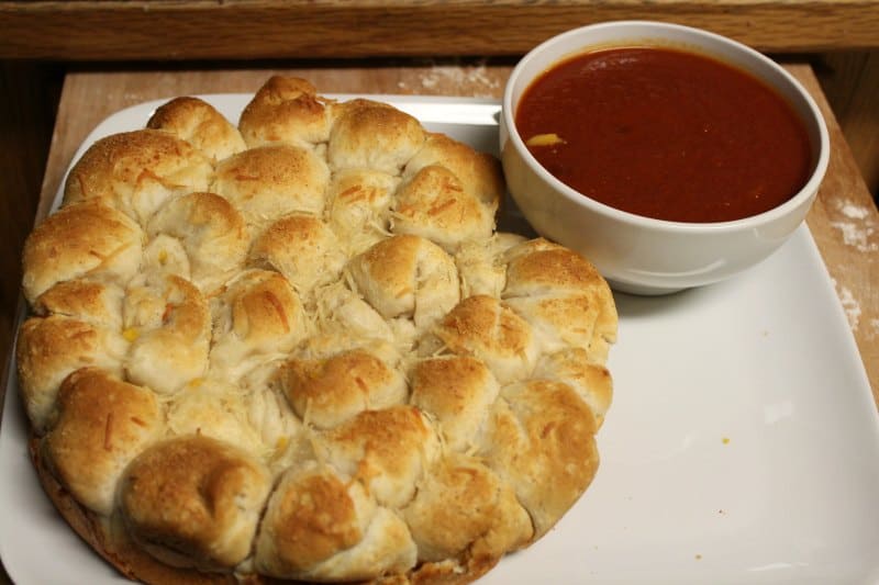 White platter with biscuit balls and a bowl of marinara sauce