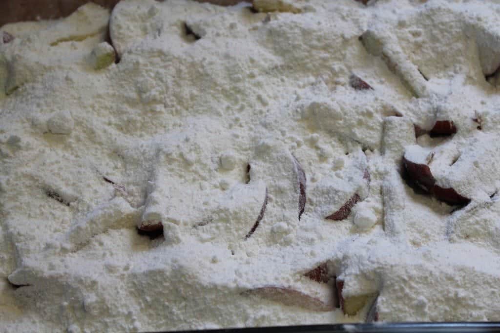 Dry cake mix over apple slices in a baking dish