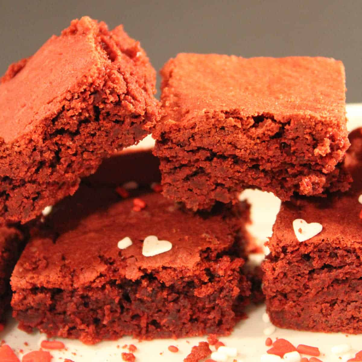 Red Velvet Brownies from Cake Mix stacked on a white plate with heart sprinkles