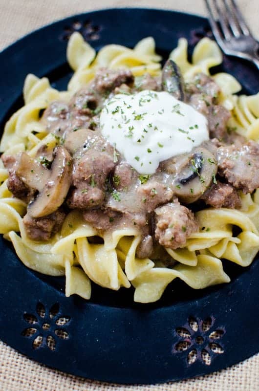 Easy Crock Pot Beef Stroganoff with a sour cream garnish on a blue plate
