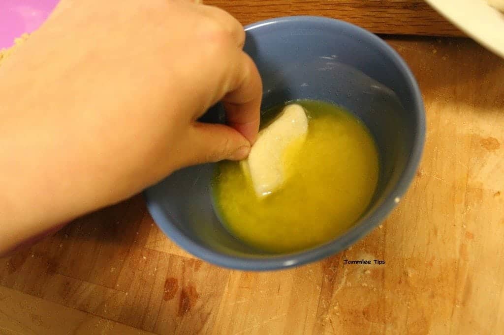 Refrigerator biscuit dough in melted butter in a blue bowl for crockpot monkey bread