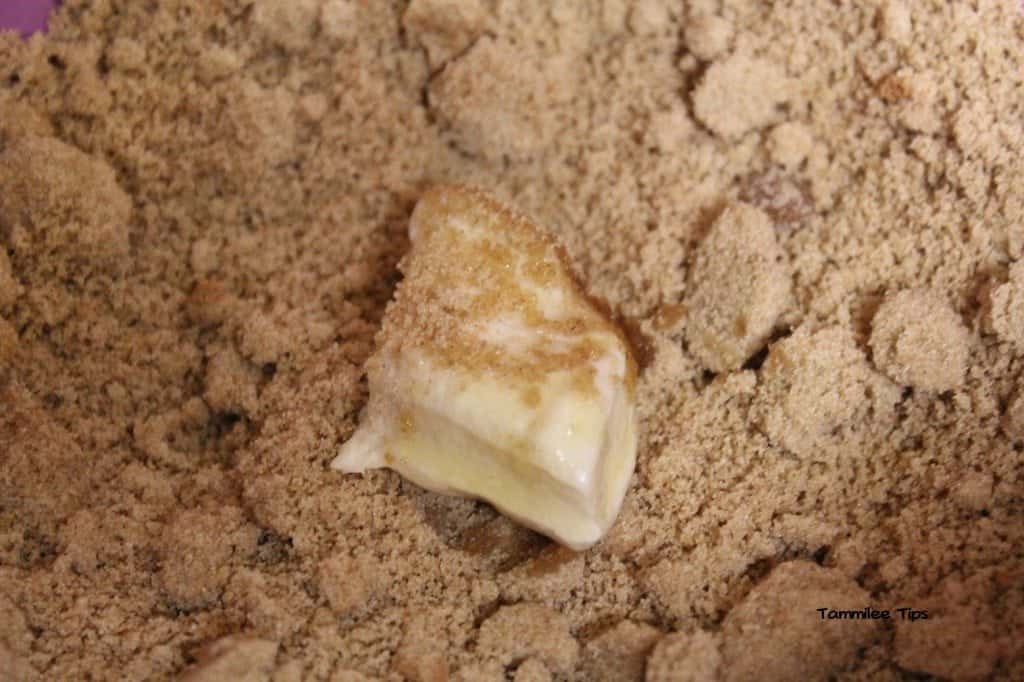 refrigerator biscuit dough coated in butter in a bowl of cinnamon and brown sugar for slow cooker monkey bread