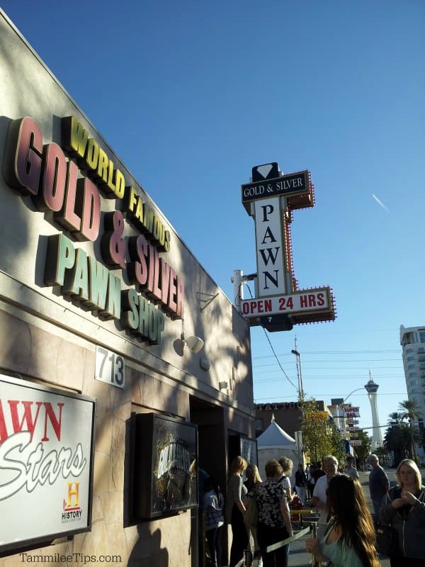 World Famous Gold & Silver Pawn Shop sign with people standing below it. 
