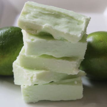 2 Ingredient Key Lime Fudge stacked on a white plate next to limes