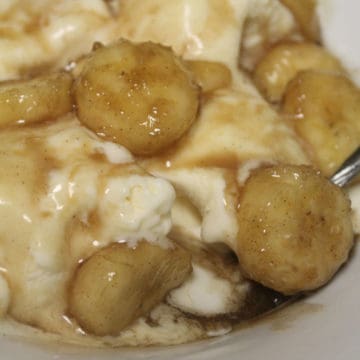 Crock Pot Bananas Foster in a white bowl with vanilla ice cream