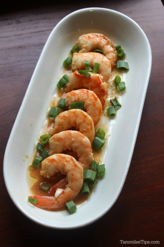 Spicy BBQ shrimp on a white platter with green onions