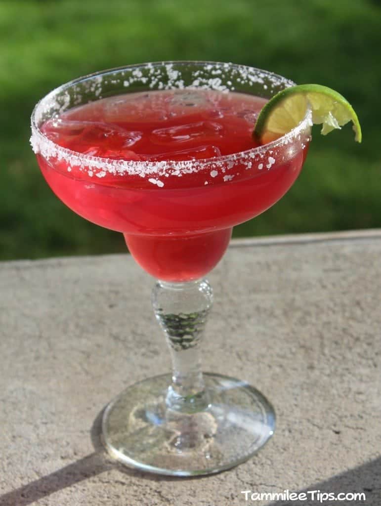 Copy Cat Chevys Sunburn Margarita with a lime wedge on a concrete porch with grass in the background