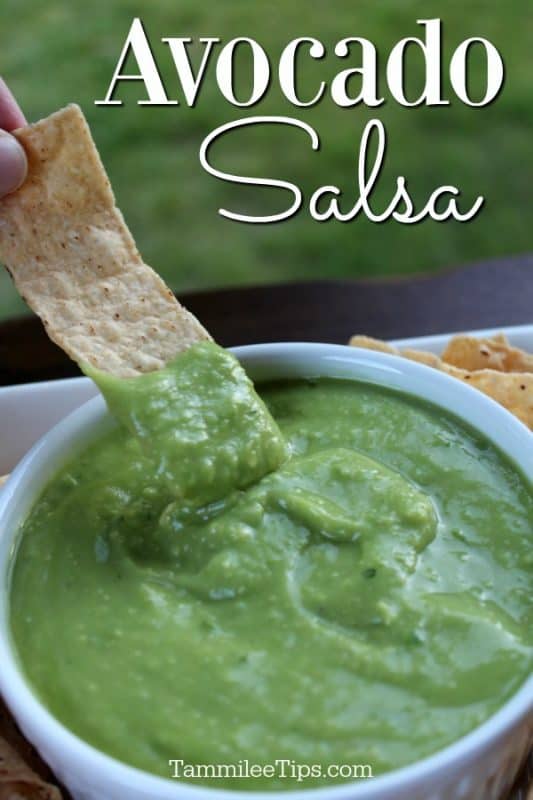 Avocado Salsa over a bowl of salsa with a tortilla chip dipping into it. 