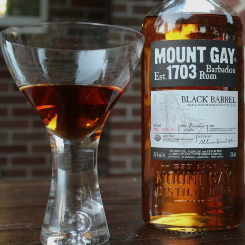 Maple old fashioned in a martini glass next to a bottle of Mount Gay Black Barrel Rum