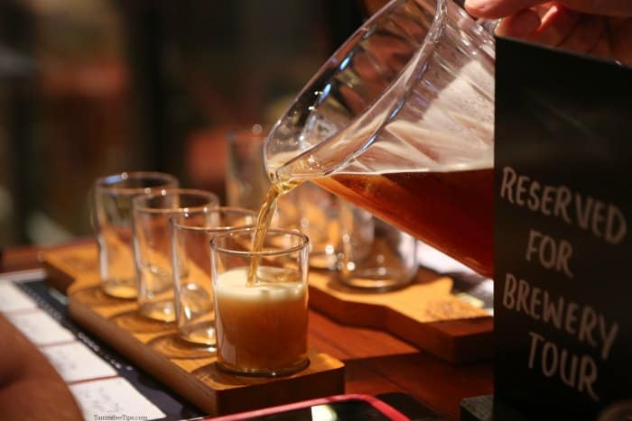 Beer pouring into a flight of glasses on a wood board