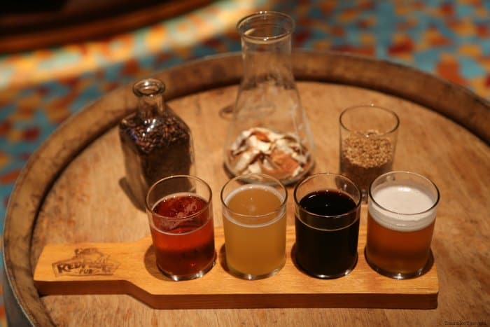 Flight of beer glasses on a RedFrog Pub board with jars of spices