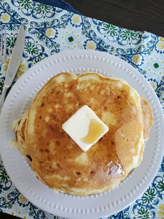 Cracker Barrel pancakes on a white plate with a square of butter and syrup