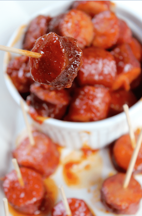 Spicy barbecue kielbasa in a bowl with one piece on a toothpick