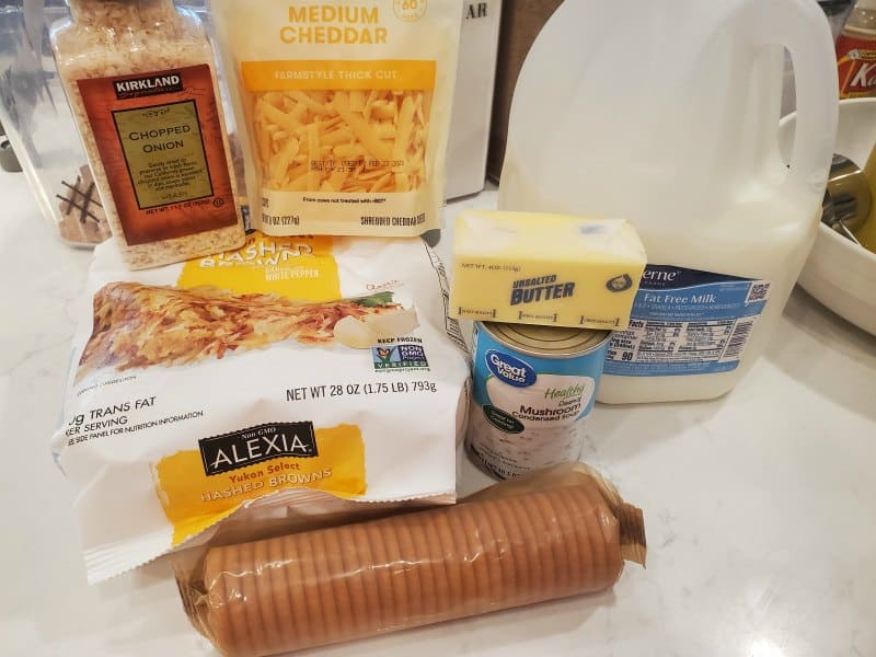 crockpot cheesy hashbrown ingredients, chopped onion, cheddar cheese, milk, frozen hashbrowns, butter, crackers, and cream of mushroom soup