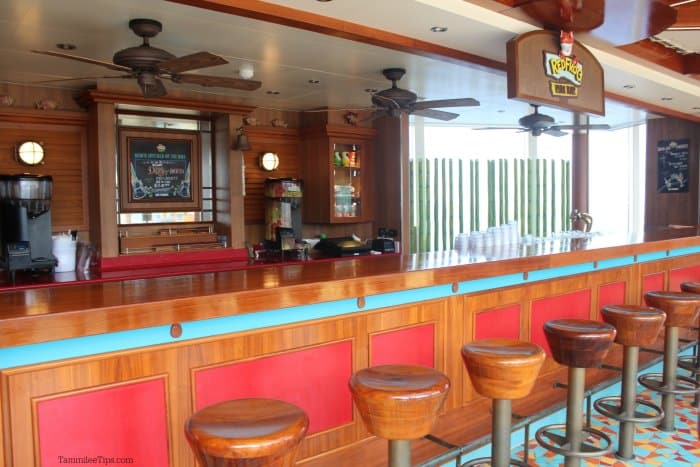 Wood topped stools at a bar with a RedFrog Rum Bar sign and outdoor fans