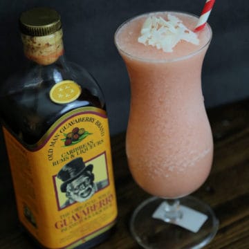 Guavaberry Colada in a hurricane glass next to a bottle of Guavaberry