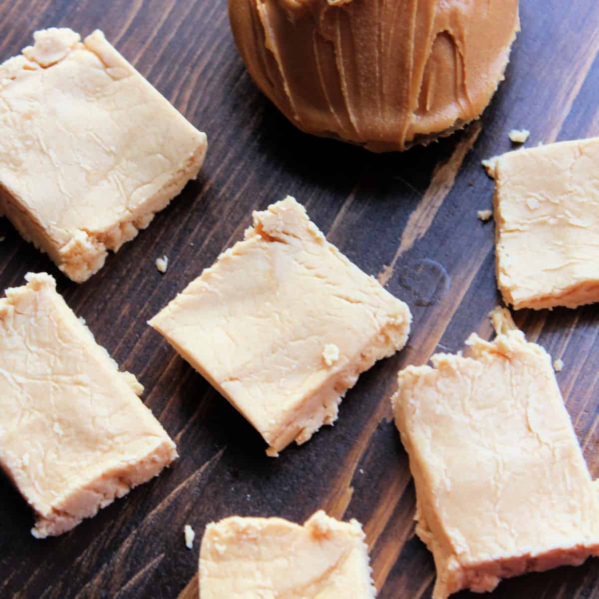 No Bake Peanut Butter Fudge next to a spoon with peanut butter on a wood board