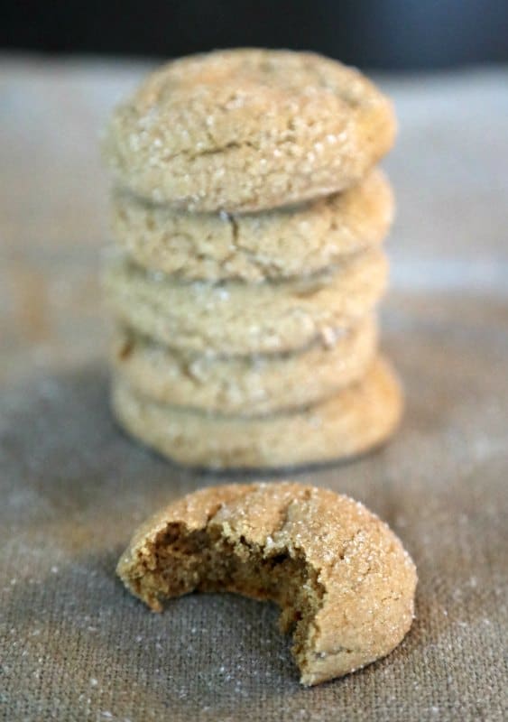 Stack of soft molasses cookies on burlap with one cookie showing a bite out of it. 
