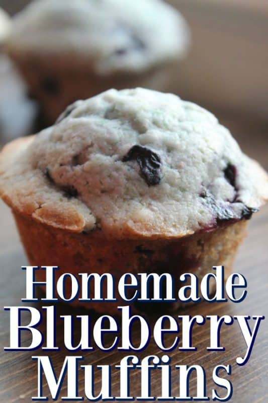 Homemade blueberry muffins next to a muffin on a cutting board. 