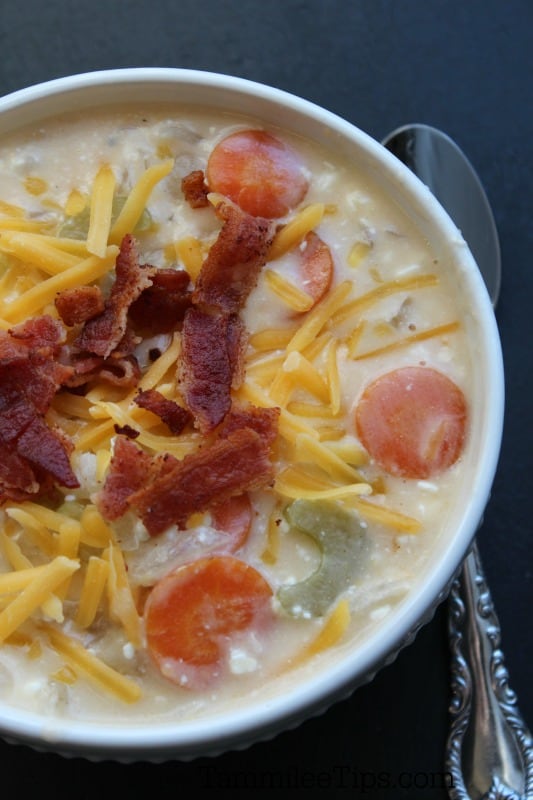 Beer cheese soup with bacon garnish in a white bowl with a spoon next to it
