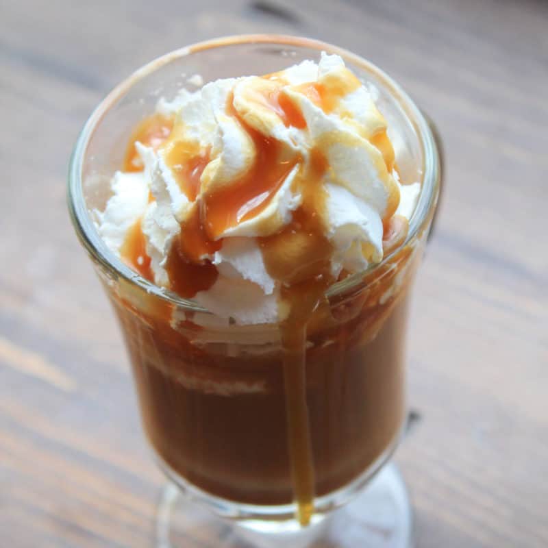 Caramel latte in a glass mug garnished with whipped cream and caramel
