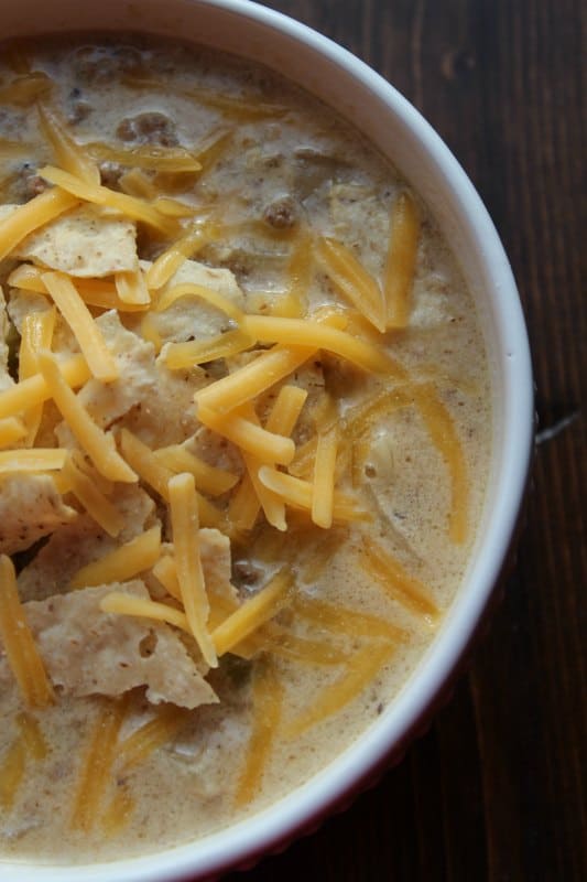 white bowl filled with soup, tortilla chips, and shredded cheese