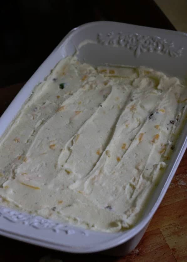 mashed potatoes with cheese spread in a white baking dish