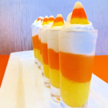 Candy Corn Cheesecake Mousse in small glasses lined on a white platter