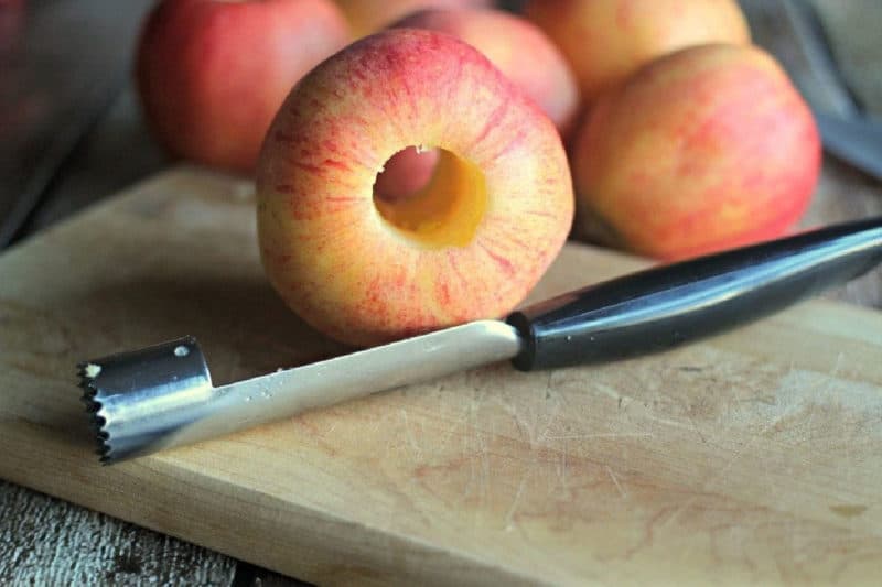 Apple corer and red apples on a wood cutting board