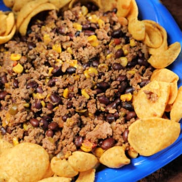 Mexican chili surrounded by fritos on a blue plate