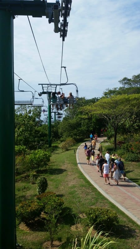 Ski lift over tropical plants and people walking on a walkway