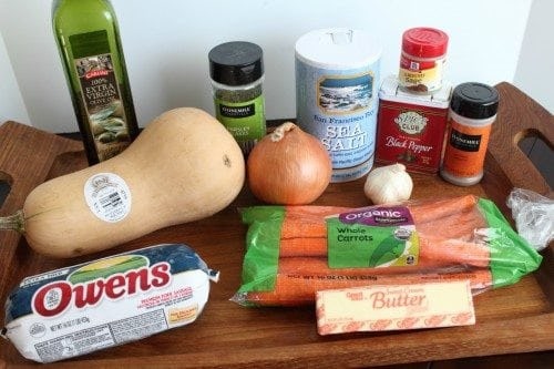 olive oil, butternut squash, sausage, carrots, butter, onion, salt, pepper, and spices on a cutting board