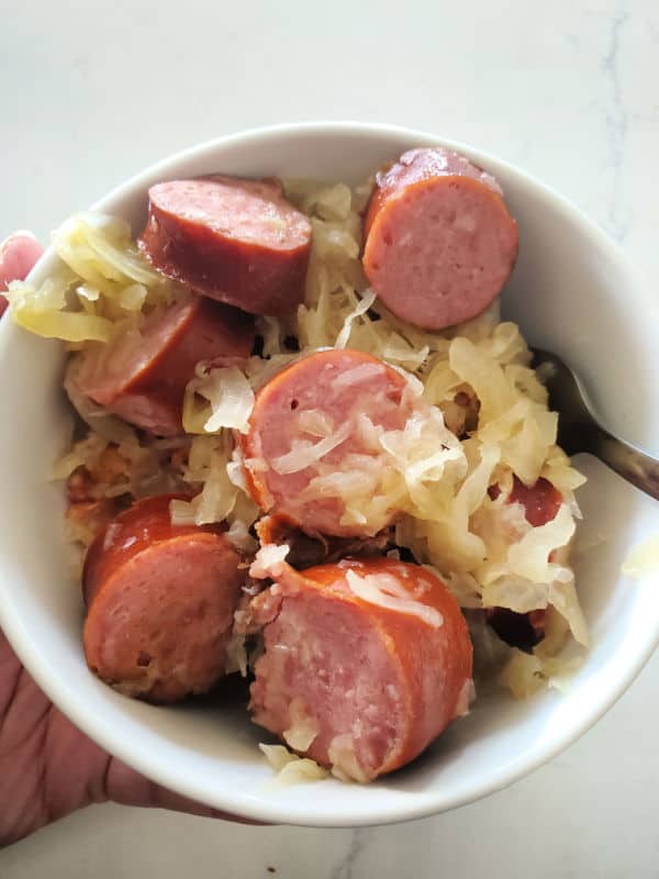 Kielabasa and sauerkraut in a white bowl with a fork