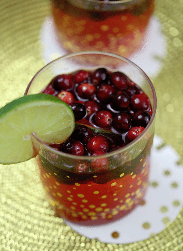cranberry lime cocktail in a spotted glass with a lime wheel