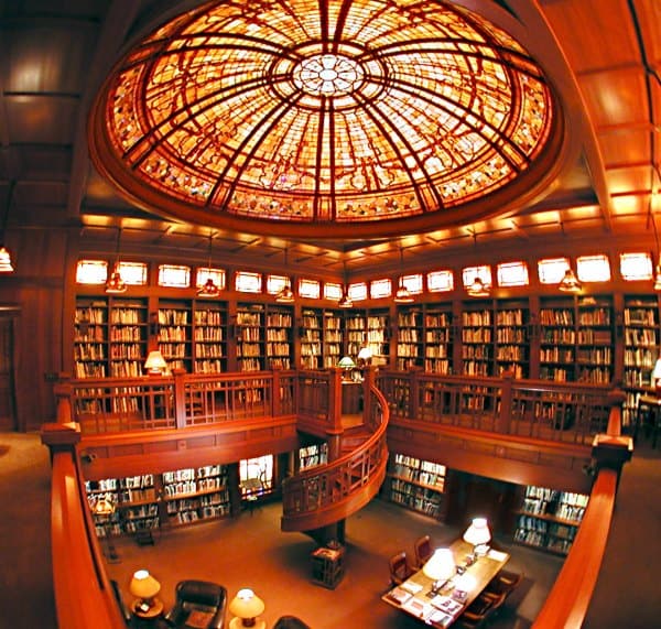 Large two story library with a spiral staircase and large ornate art sunlight 