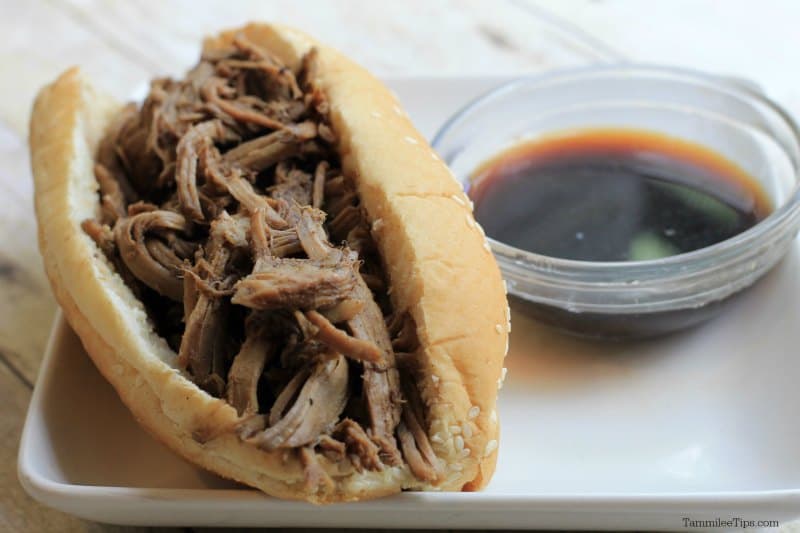 Balsamic French Dip sandwich in a bun on a white plate next to a small bowl of Au Jus sauce