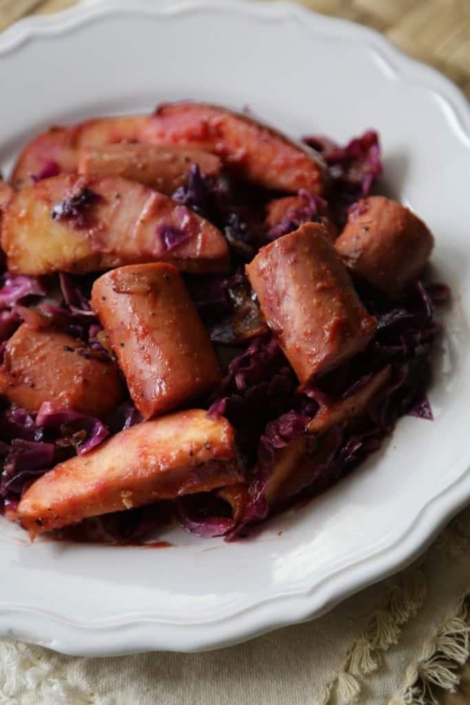 Kielbasa and apple slices with red cabbage in a white bowl