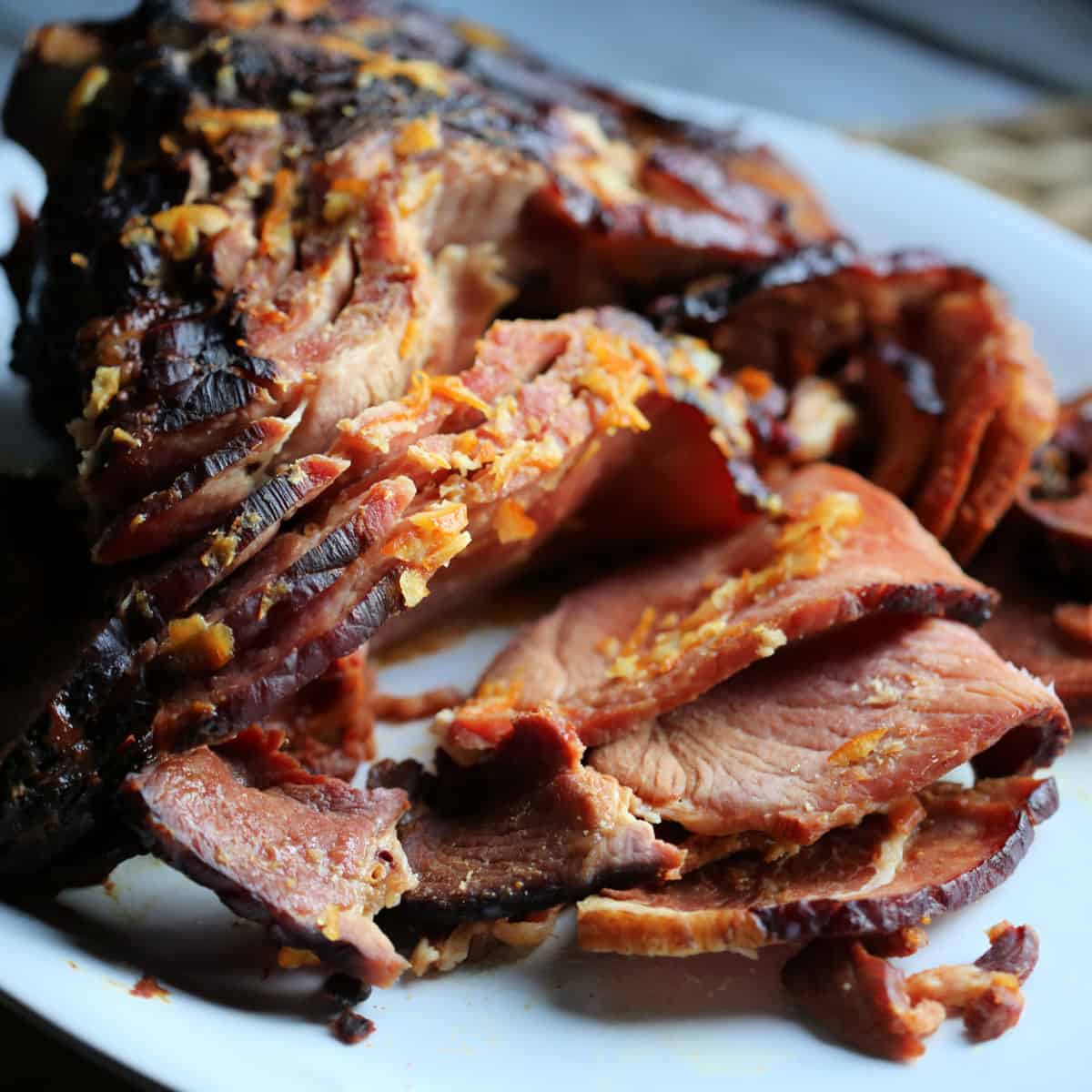 Orange Glazed ham with orange zest on a white plate