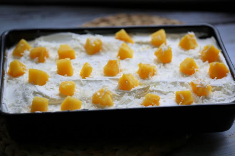 Pina Colada Poke Cake in a cake pan topped with pineapple chunks