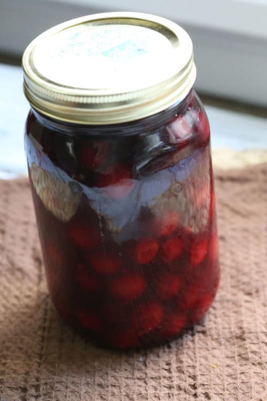 cherry moonshine in a sealed mason jar on a brown napkin