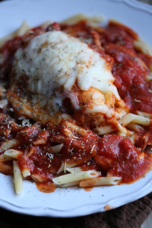 Chicen parmesan covered in mozzarella on penne pasta with sauce