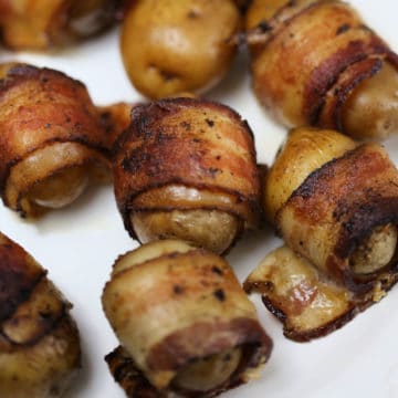 Bacon wrapped baby potatoes on a white plate