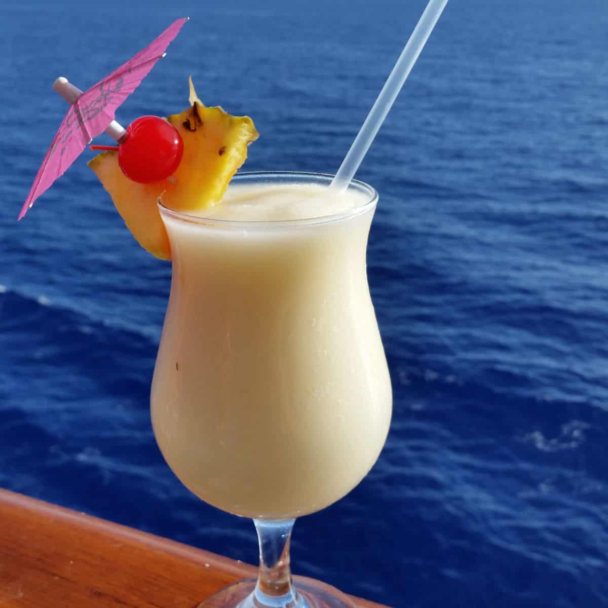Caribbean Colada in a hurricane glass with pineapple wedge and cherry garnish