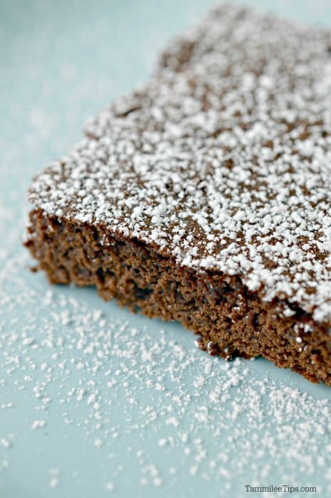 Chocolate brownie square dusted in powdered sugar on a light blue plate